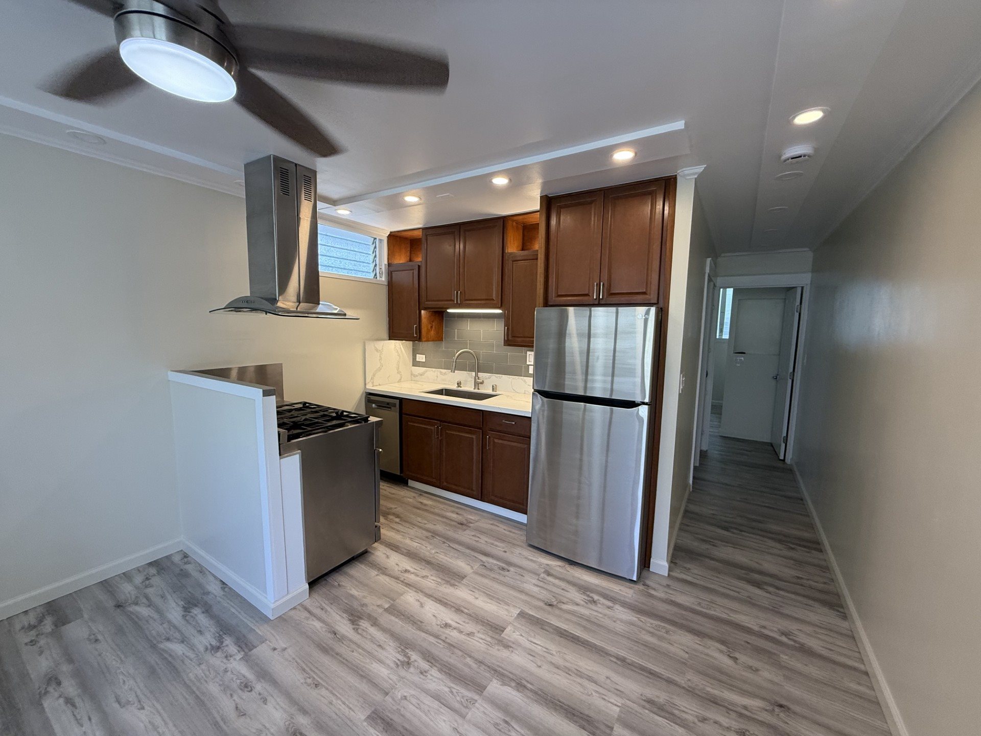 A modern kitchen with a wood grain floor and white walls.